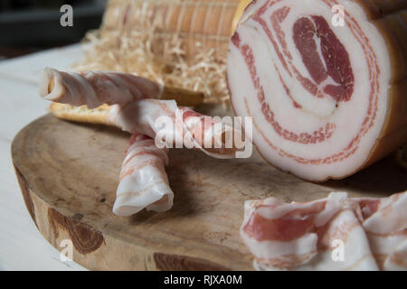 Libre de hacher en bois avec tranches de pancetta italienne faite à Piacenza, Italie du nord. Les tranches sont tordus autour de bâtonnets de pain appelé grissini j Banque D'Images