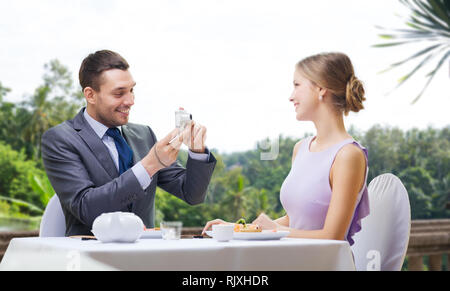 Man photographing woman par l'appareil photo au restaurant Banque D'Images
