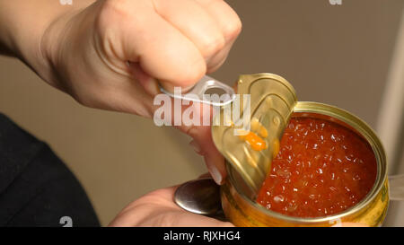 Femme les mains ouvertes en métal avec du caviar rouge Banque D'Images