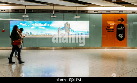 London Heathrow, Royaume-Uni, 5 févr. 2019 : deux passagers passant par un signe et l'image de Tower Bridge Bienvenue écrit à l'aéroport de Heathrow Banque D'Images