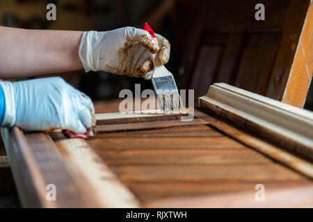 Main tenant un pinceau appliquer de la peinture sur meubles en bois Banque D'Images