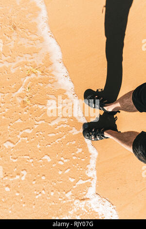 High angle view of mans pieds dans l'eau par bassin pour enfants sur la plage, vertical Banque D'Images