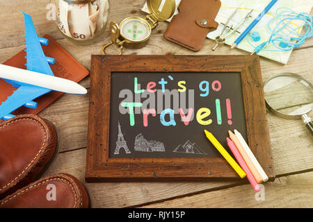 Let's go travel inscription sur le tableau noir. Pot avec de l'argent pour un billet, avion, cartes, passeport, et d'autres trucs pour l'aventure sur la table Banque D'Images