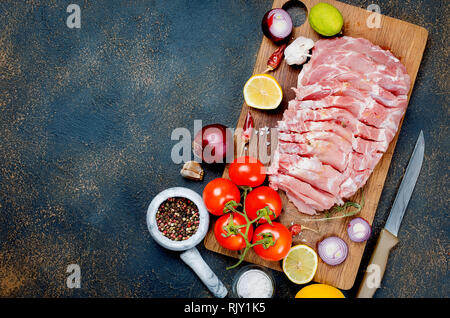 Gros morceau de matière première pour la cuisson du porc aux légumes et épices sur fond sombre, cuisine, vue du dessus, copy space Banque D'Images