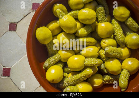 Olives farcies aux cornichons marinés servis sur la cuvette d'argile. Passage tourné sur table mosaïque tuiles vernissées Banque D'Images