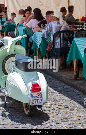 Un classique super 125 Vespa scooter parqué par un restaurant avec salle à manger à l'extérieur de personnes dans le Trastevere, Rome, Italie. Banque D'Images