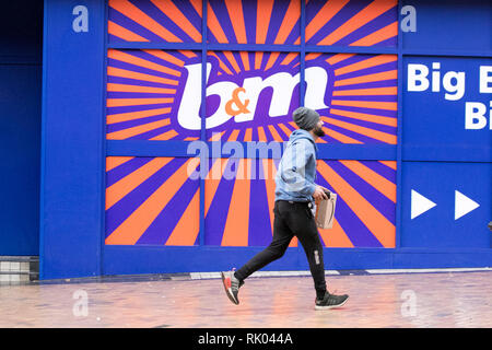 Blackpool, Lancashire. 8 février 2019. Météo Royaume-Uni. Un homme se précipitant dans les magasins pour un début de journée humide et venteux, pour les clients à prix réduit du B&M Bargains local. Crédit : MediaWorldImages/AlamyLiveNews. Banque D'Images