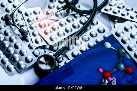 Stéthoscope mis sur manuel de chimie médicinale et des comprimés dans l'argent d'aluminium blister on white table des médecin. La cardiologie et la guérison du cœur Banque D'Images