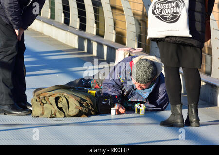 Londres, Angleterre, Royaume-Uni. Millennium Bridge : Ben Wilson - 'Chewing-gum' homme . La peinture d'une petite œuvre d'art sur un morceau de chewing-gum, c1-1.5cm... Banque D'Images