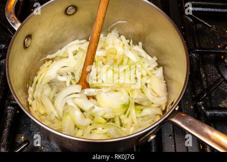 Faire frire les oignons dans une casserole sur une cuisinière. Banque D'Images