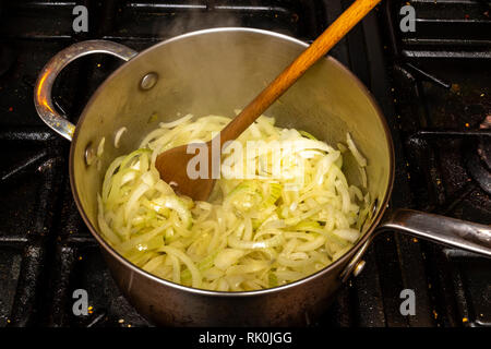Faire frire les oignons dans une casserole sur une cuisinière. Banque D'Images