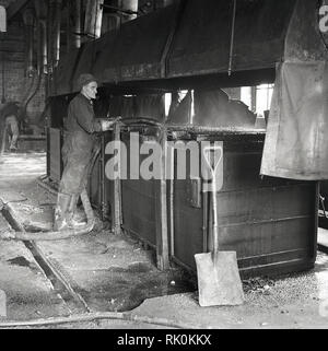 Années 1950, historique, un homme en bleu de travail en usine sur les matières premières utilisées dans la fabrication de carbone-zinc, England, UK Banque D'Images