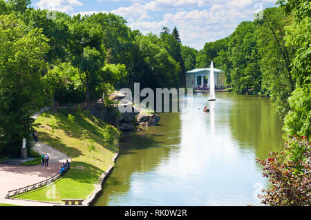 Paysage du Parc Sofiyivka à Ouman, en Ukraine. Un bateau sur un grand lac à proximité d'une fontaine, d'énormes rochers et d'arbres des deux côtés sur une journée ensoleillée. S Banque D'Images