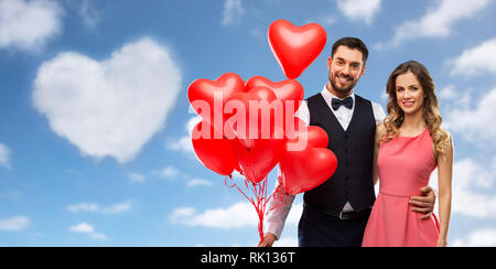 Couple heureux avec des ballons en forme de coeur rouge Banque D'Images