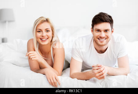 Heureux couple lying in bed at home Banque D'Images