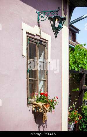 Sighisoara, Roumanie - 23 juin 2013 : façade rose avec des fenêtres blanches et lampe de rue sur une vieille maison rose de la vieille ville de Sighisoara, Roumanie centre Banque D'Images