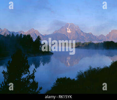 USA, Wyoming, Grand Teton National Park, le brouillard du matin s'attarde à la base du Mt. Moran qui reflète dans la Snake River d'Oxbow Bend. Banque D'Images