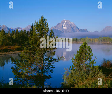 USA, Wyoming, Grand Teton National Park, le brouillard du matin s'attarde à la base du Mt. Moran qui reflète dans la Snake River d'Oxbow Bend. Banque D'Images