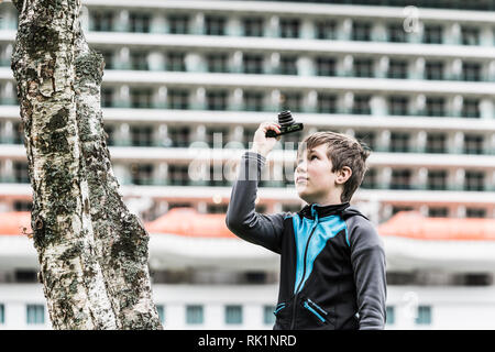 Portrait de jeune garçon pointant vers le haut de l'appareil photo par tree Banque D'Images