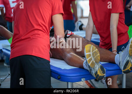 Étendu sur un lit de l'athlète tout en ayant les jambes massées après un entraînement physiques sportives. Banque D'Images