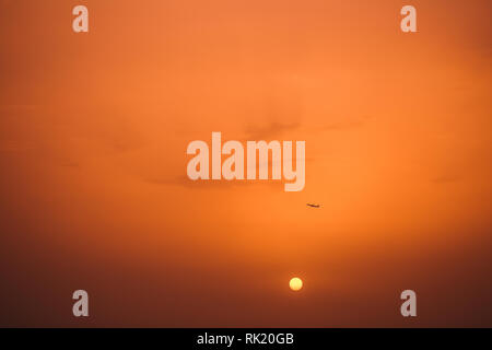 Silhouette sombre d'avion en distance dans l'air et le coucher de soleil en arrière-plan. Faire décoller l'avion de l'aéroport en Turquie. Photographie couleur horizontal Banque D'Images