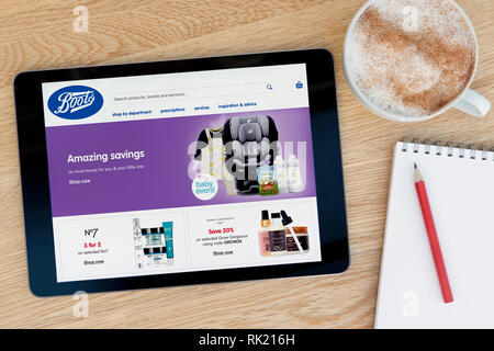Le site web présente des bottes sur un iPad tablet device qui repose sur une table en bois à côté d'un bloc-notes (usage éditorial uniquement). Banque D'Images
