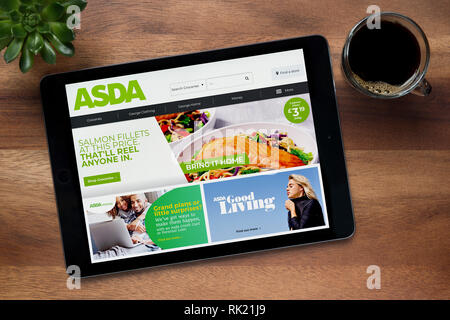 Le site internet de l'Asda est vu sur un iPad tablet, sur une table en bois avec une machine à expresso et d'une plante (usage éditorial uniquement). Banque D'Images