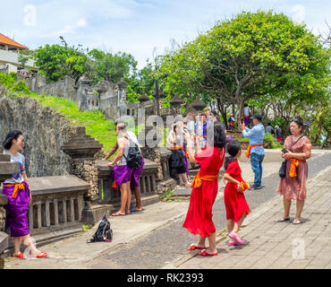 Les touristes chinois portant des jupes violet visiter Temple d'Uluwatu Bali Indonésie. Banque D'Images