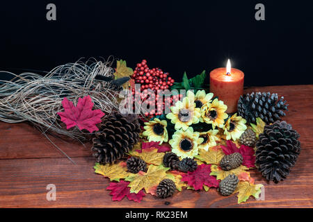 Feuilles d'érable en soie, magnifique bouquet de tournesols, givré de cocottes et bougie orange sur la table d'examen avec un arrière-plan sombre. Banque D'Images