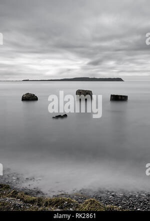 Plage de Lonely avec de gros rochers dans l'eau, l'eau et les nuages se déplaçant dans une longue exposition, dans l'arrière-plan l'île de Hiddensee en silhouette - Emplacement Banque D'Images