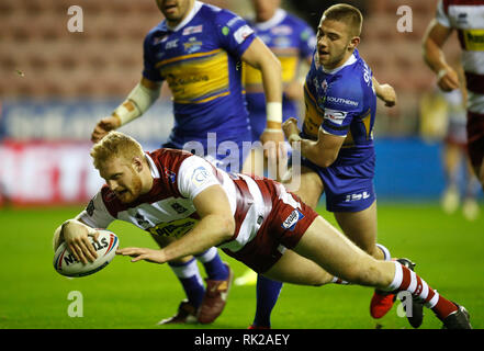 Wigan Warriors Joe Bullock va au-dessus pour un essai passé Leeds Rhinos Jack Walker au cours de la Super League Betfred match à la DW Stadium, Wigan. Banque D'Images