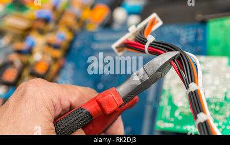 Connecteur, câbles et part avec une pince. Les déchets électroniques close-up. Travail de spécialiste technique. De vieux tas colorés jetés ordinateur portable et PC pièces. Banque D'Images