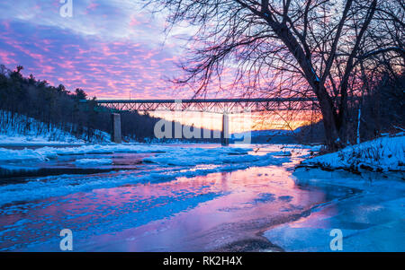 La rivière glacée reflète la vive coucher du soleil près de Milford Bridge, PA Banque D'Images