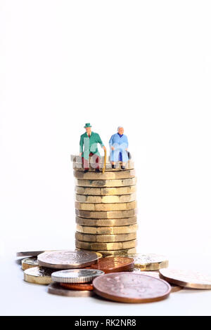 L'image conceptuelle diorama d'une figure miniature à la retraite couple assis sur une pile de pièces en livres Banque D'Images