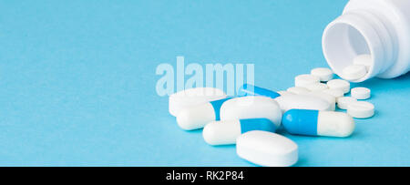 Close up pills spilling out de bouteille de pilules sur fond bleu. L'assurance médicale, de la médecine ou de la pharmacie concept. Banque D'Images