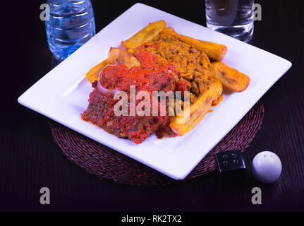 - Des repas populaires Nigerian un passage tiré d'un plat de haricots, Dodo, et ragoût de poisson dans une assiette blanche Banque D'Images