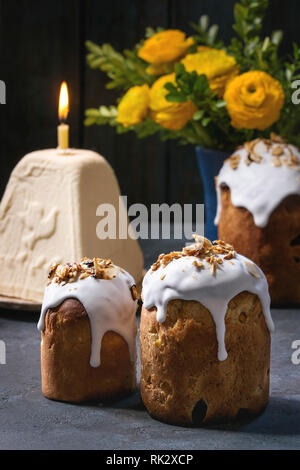 Ensemble de cuisine russe et ukrainienne Kulich gâteau de Pâques pain Paska vitrage avec des amandes, entières ou coupées en tranches, servi avec des fleurs jaunes, les oeufs colorés Banque D'Images