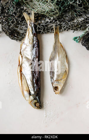 Le poisson séché ou stockfish sur les filets de pêche sur fond de marbre blanc. Mise à plat, de l'espace Banque D'Images