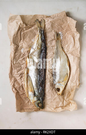 Le poisson séché ou stockfish sur papier froissé sur fond de marbre blanc. Mise à plat, de l'espace Banque D'Images