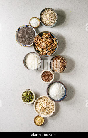 Variété de grains crus crus céréales superfood chia, lin, sésame, haricots mungo, noix, tapioca, le blé, le sarrasin, l'avoine, la noix de coco, riz en céramique Banque D'Images