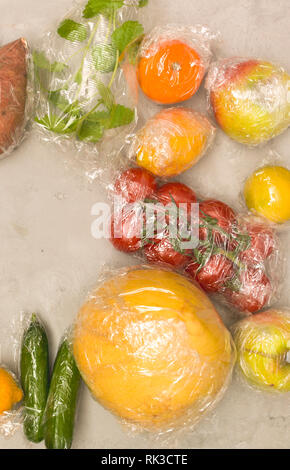 Beaucoup de différents fruits et légumes sont emballés dans un sachet en plastique, paniers sur fond de béton Banque D'Images