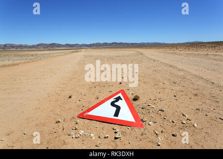 Panneau d'avertissement des virages sur la route au sol dans le désert de Namib, Namibie, Afrique Banque D'Images