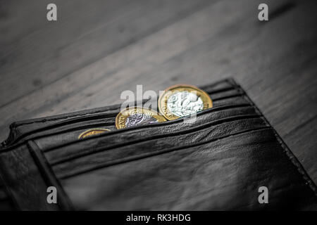 New Great British Pound GBP Coins portant sur haut de portefeuille noir sur la surface en bois. La richesse, l'argent, l'argent comptant, le changement. Banque D'Images