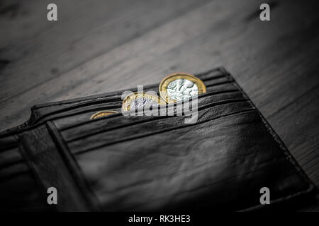 New Great British Pound GBP Coins portant sur haut de portefeuille noir sur la surface en bois. La richesse, l'argent, l'argent comptant, le changement. Banque D'Images