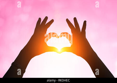 Mains sous une silhouette en forme de cœur .fond flou de la Saint-Valentin concept. Carte de Saint Valentin. Des tons pastels.coeur blanc multicolore Banque D'Images