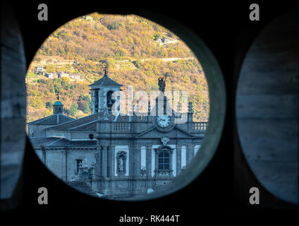Vue de la façade baroque de l'église romane Collegiata di San Giovanni Battista grâce à l'ouverture d'un trou circulaire à l'intérieur de Palazzo Malacrida, Morbegno Banque D'Images