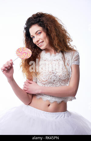 Portrait of cute smiling young girl eating lollipop. Studio portrait sur fond blanc Banque D'Images