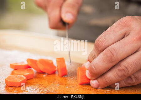 Carotte de trancher. Faire cuire les mains avec couteau, close-up photo avec selective focus Banque D'Images
