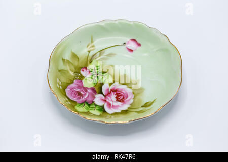 Un petit plat décoratif vert avec des petites fleurs roses sur elle Banque D'Images