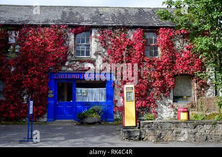 La maison de la Poterie Callura avec un bleu porte avant et fenêtre avant. En face de la maison est une ancienne pompe à essence. Mountshannon, comté de clar Banque D'Images